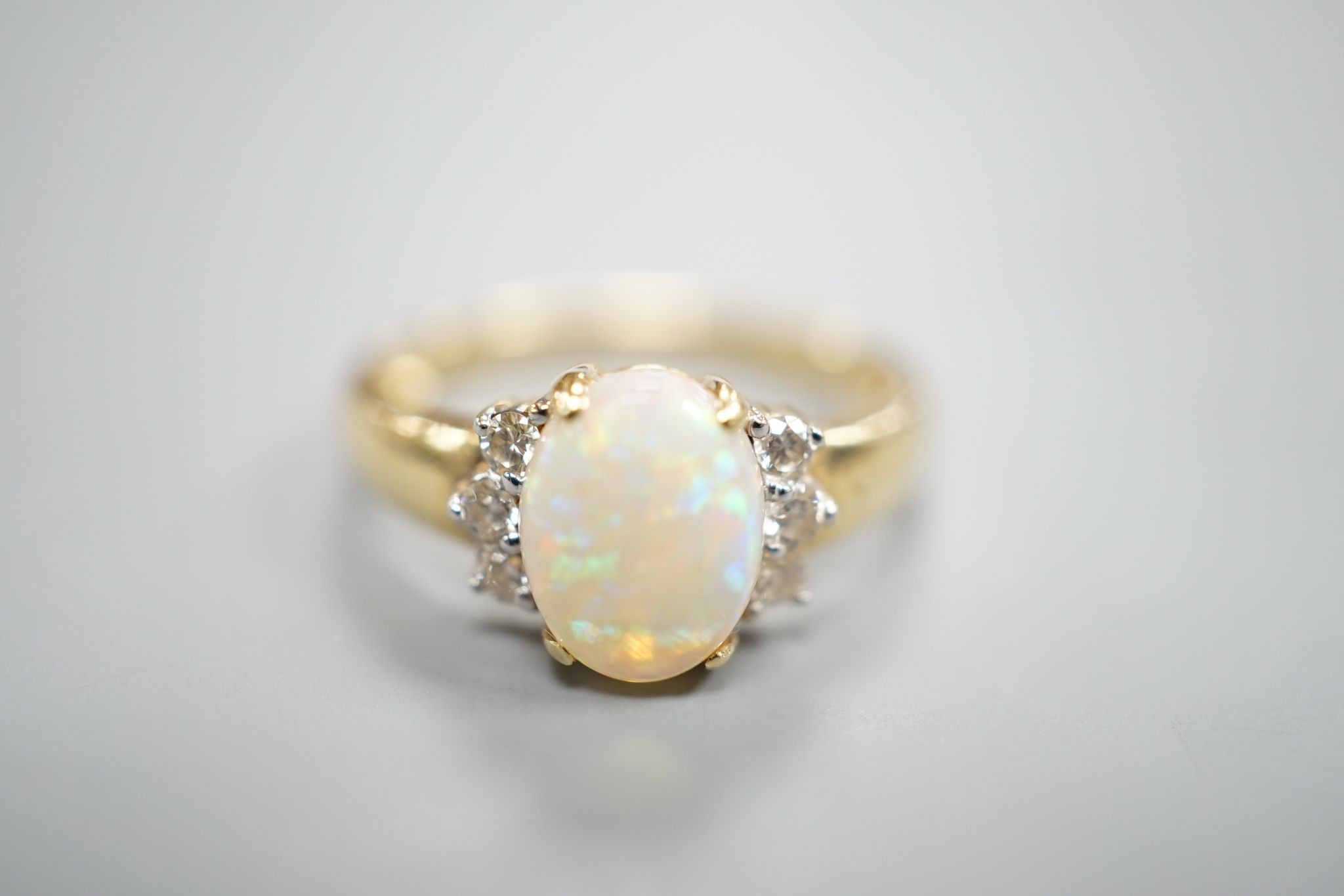 A modern 14k yellow metal, oval white opal and six stone diamond set cluster ring, size N, gross weight 2.9 grams.